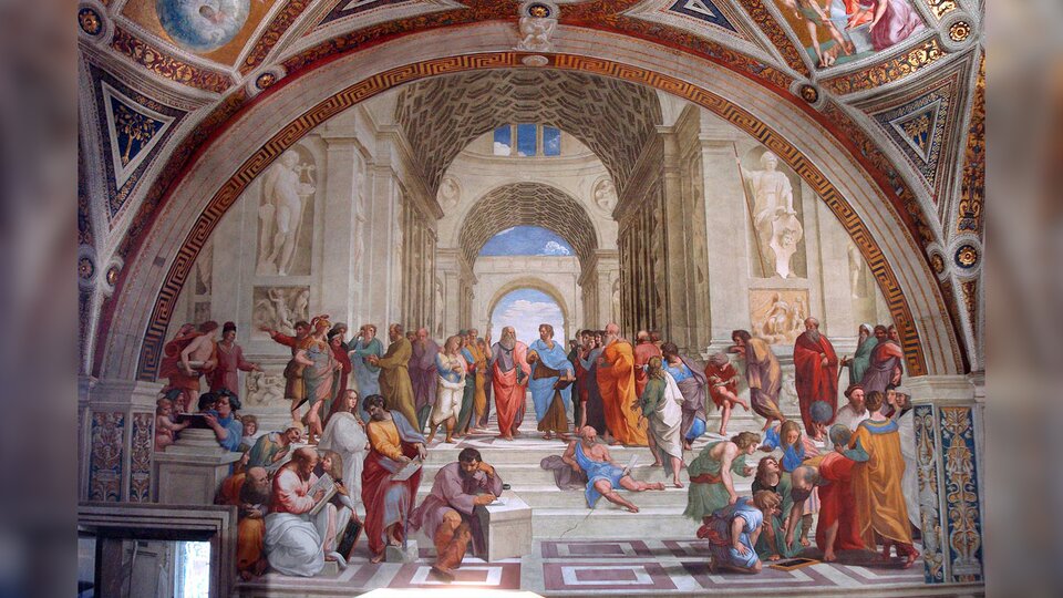 Obraz przedstawia szkołę ateńską. W przestronnym, starożytnym budynku, pełnym rzeźb i płaskorzeźb znajduje się liczna grupa mężczyzn. Mężczyźni chodzą, siedzą, rozmawiają ze sobą, gestykulują.