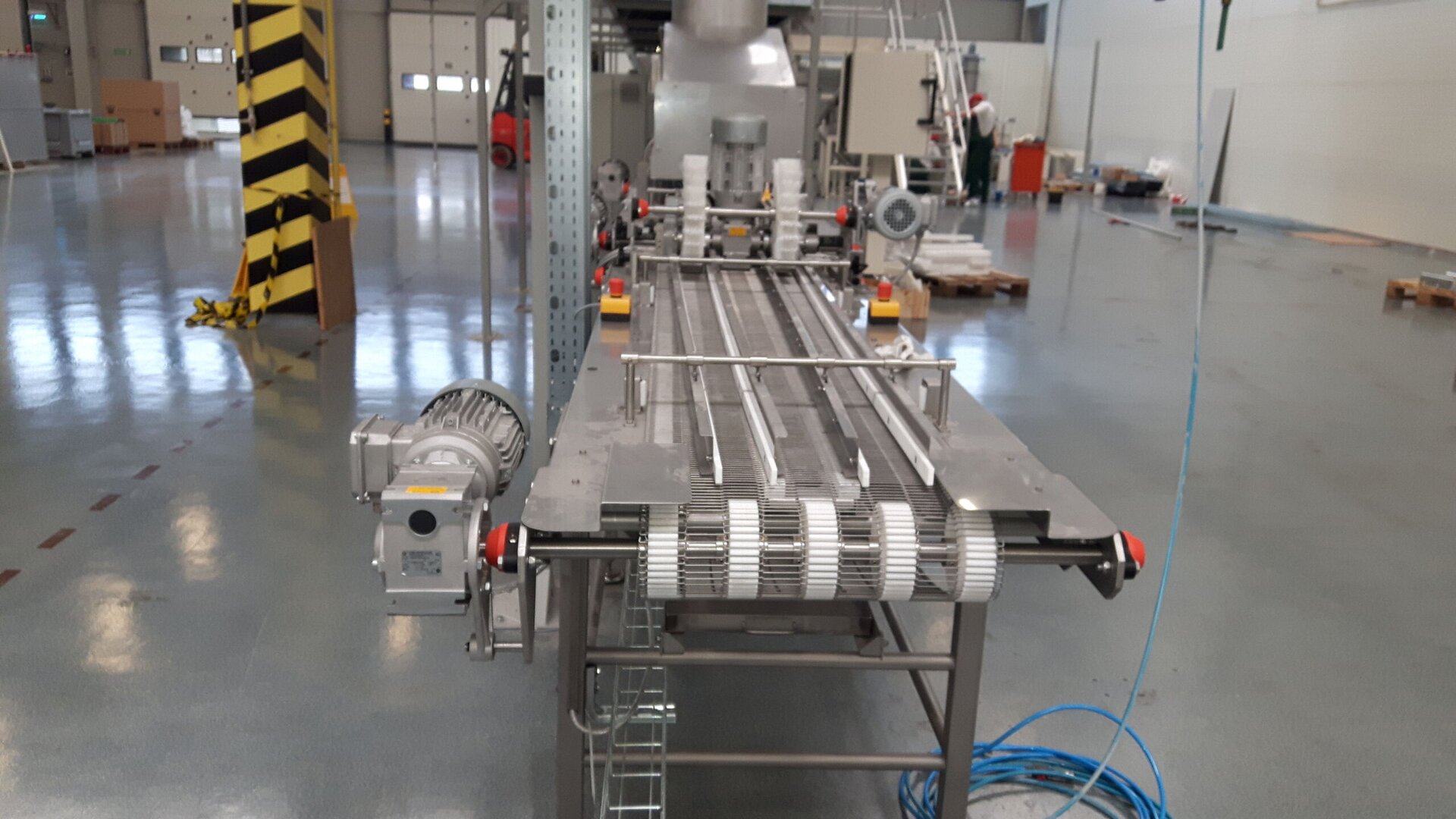 Zdjęcie przedstawia transporter taśmowy. Jest to długi stół, na którego środku znajdują się dwa miejsca na rury.