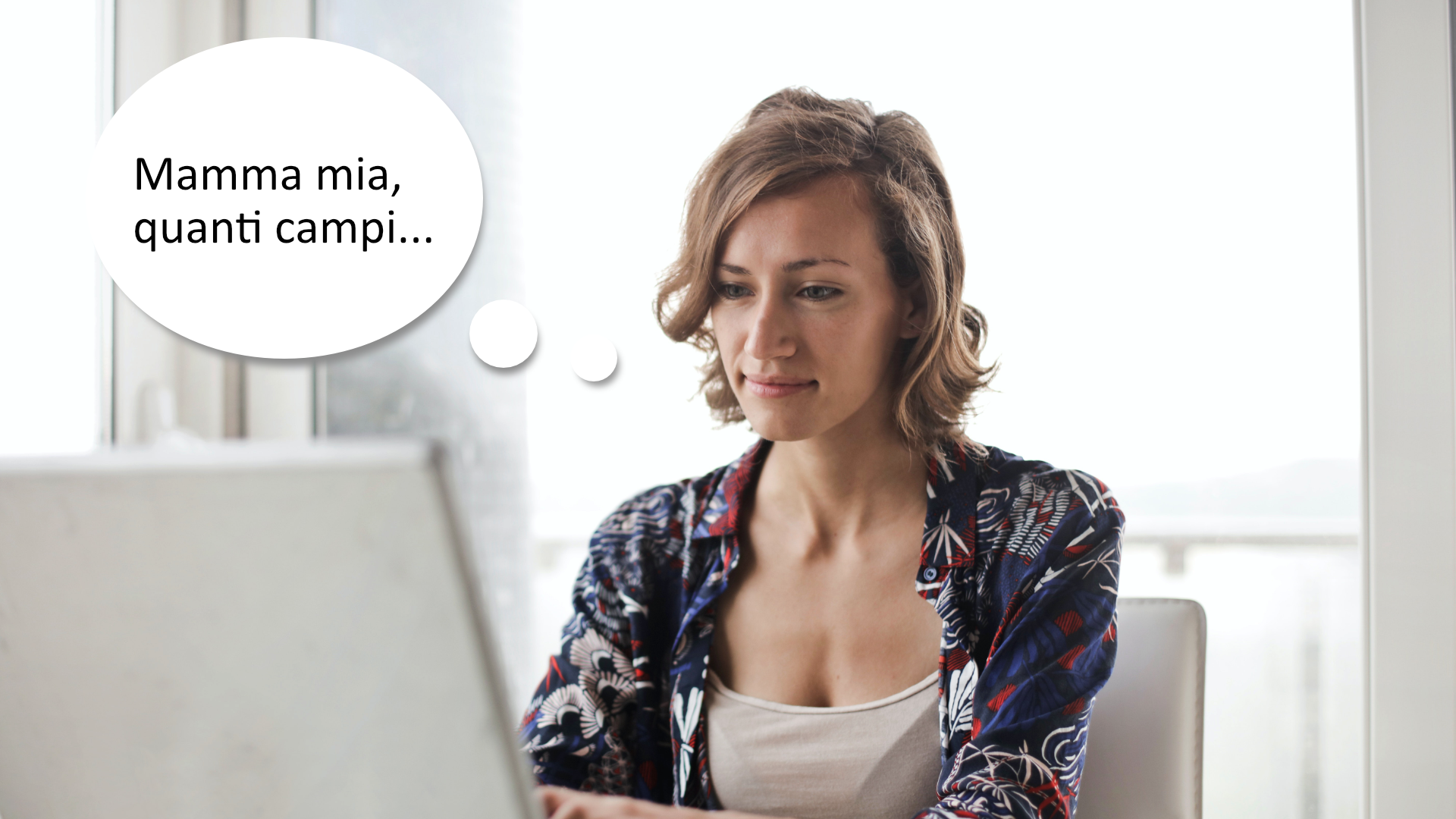 Zdjęcie przedstawia młoda kobietę, która siedzi przed ekranem komputera. Obok kobiety znajduje się dymek z tekstem: "Mamma mia, quanti campi..."
