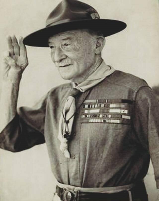 Czarno‑biała fotografia przedstawia starszego mężczyznę w mundurze z krótkim rękawem i odznaczeniami na piersi. Na głowie ma kapelusz z szerokim rondem. Mężczyzna unosi prawą rękę w geście salutowania. Ma krótki wąs, wyraźne zmarszczki na twarzy oraz lekko garbaty nos.