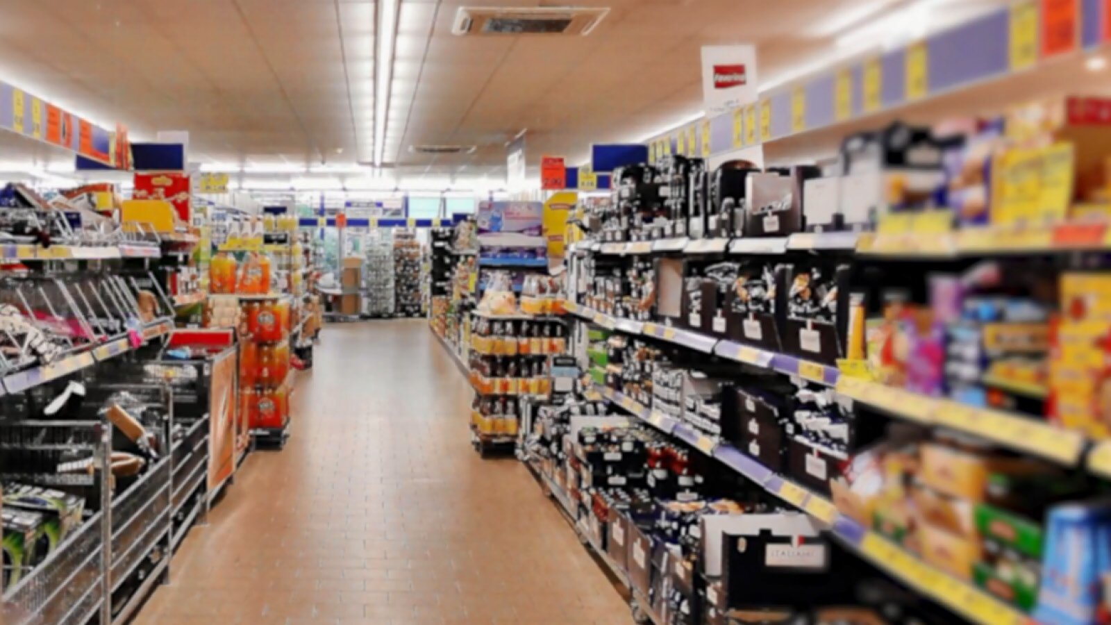 Sich gut umschauen. Mach dir die Mühe und schaue nach den Waren ganz oben und ganz unten in den Regalen. Dort verstecken sich die billigeren Produkte. Die Produkte auf Augenhöhe sind meist teurer. Natürlich wollen die Supermärkte diese Produkte am liebsten verkaufen, da bei ihnen die Marge am höchsten ist.
Ilustracja przedstawia wnętrze supermarketu. Jest to duża dobrze oświetlona przestrzeń z regałami, na których znajdują się starannie poukładane towary.