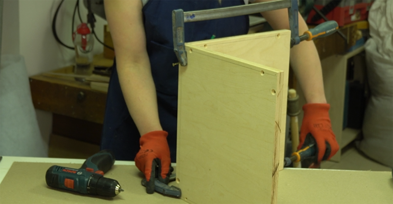 Na zdjęciu przedstawiono tapicera, który połączył dwie ścianki skrzyni. Elementy te zostały dodatkowo połączone zaciskami.