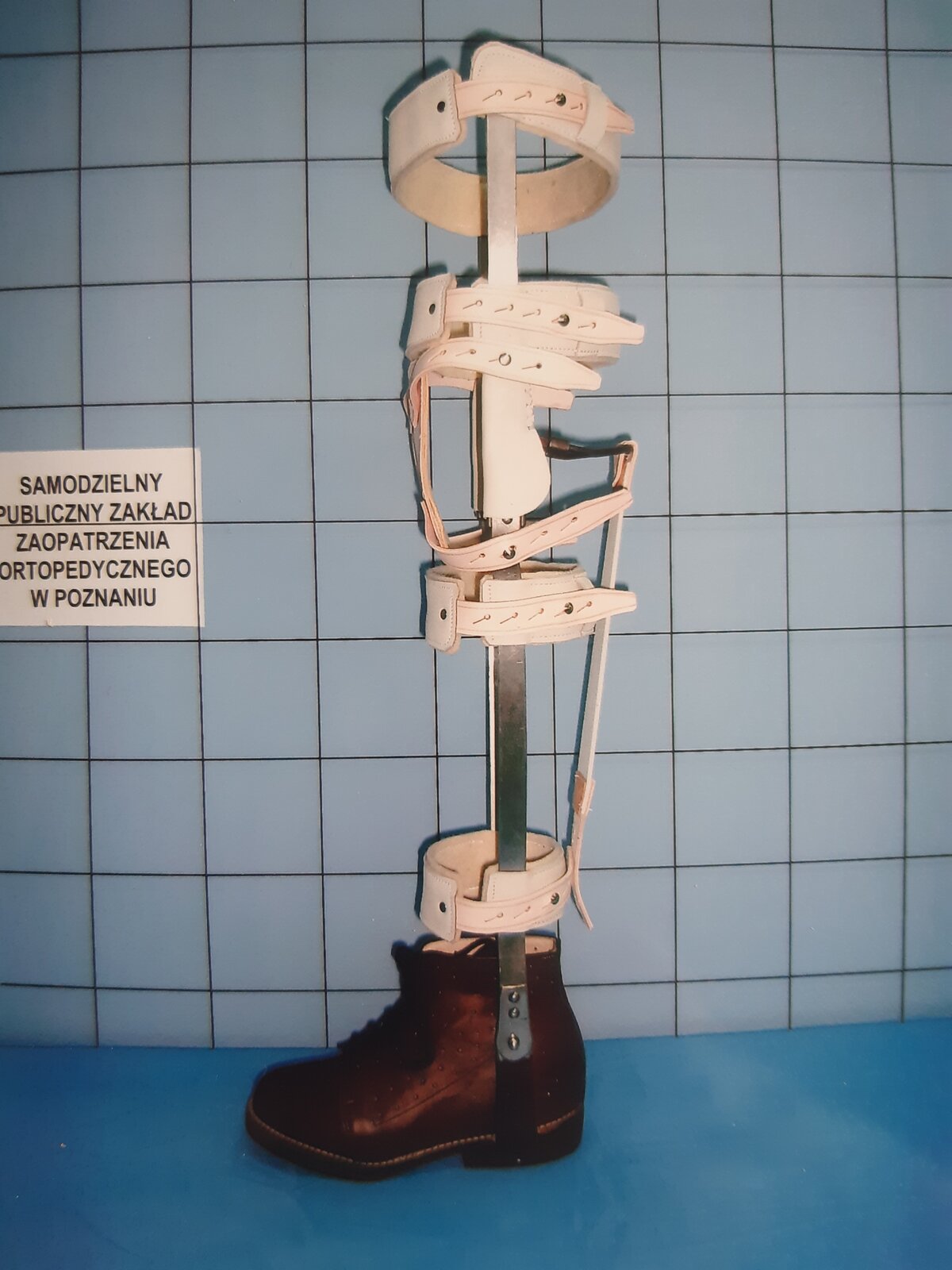 Zdjęcie przedstawia but ortopedyczny, do którego przymocowane są szyny i opaski na wysokość całej kończyny dolnej.