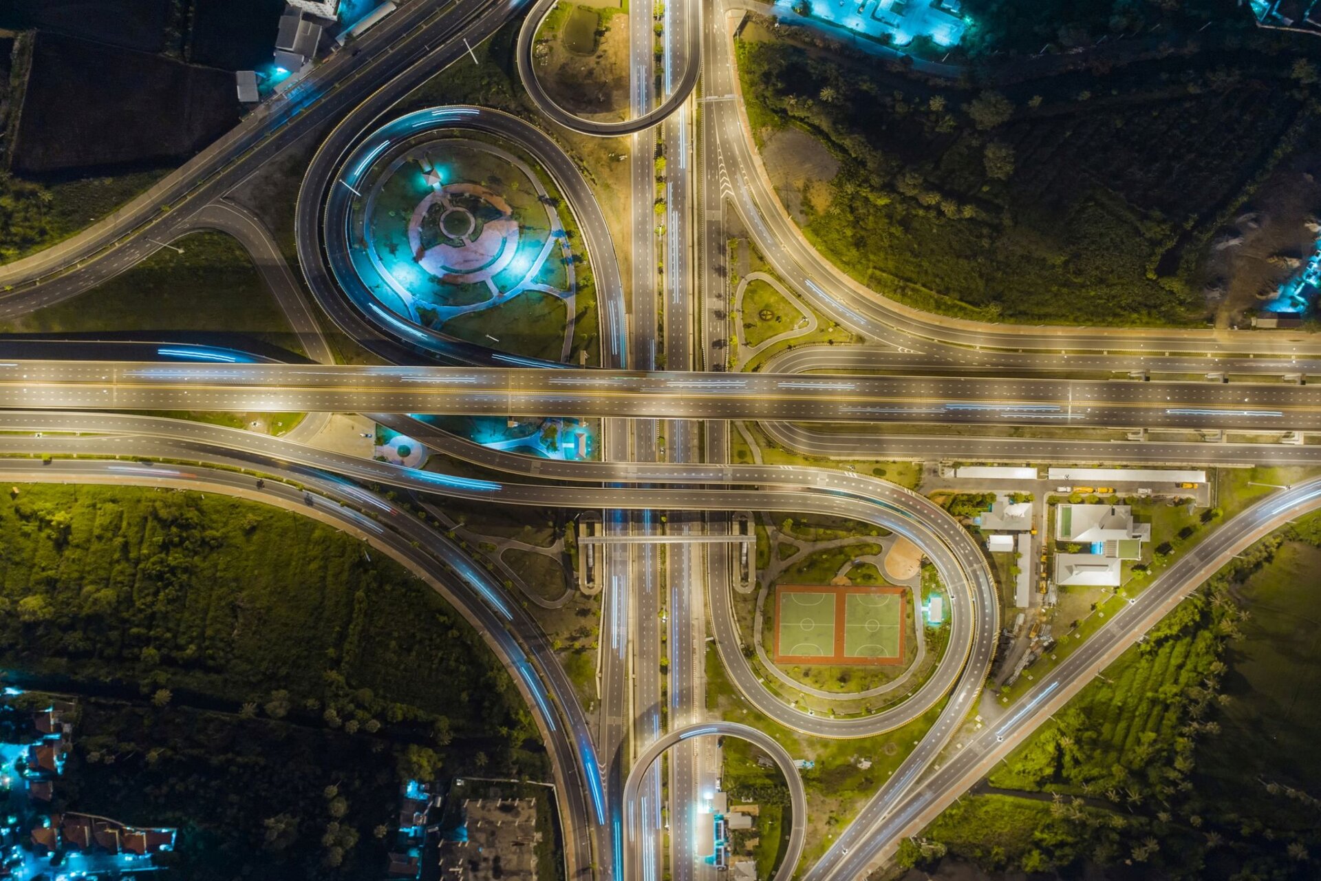 Fotografia wykonana z perspektywy lotu ptaka ukazuje nowoczesny węzeł komunikacyjny w kształcie wielopoziomowego skrzyżowania.