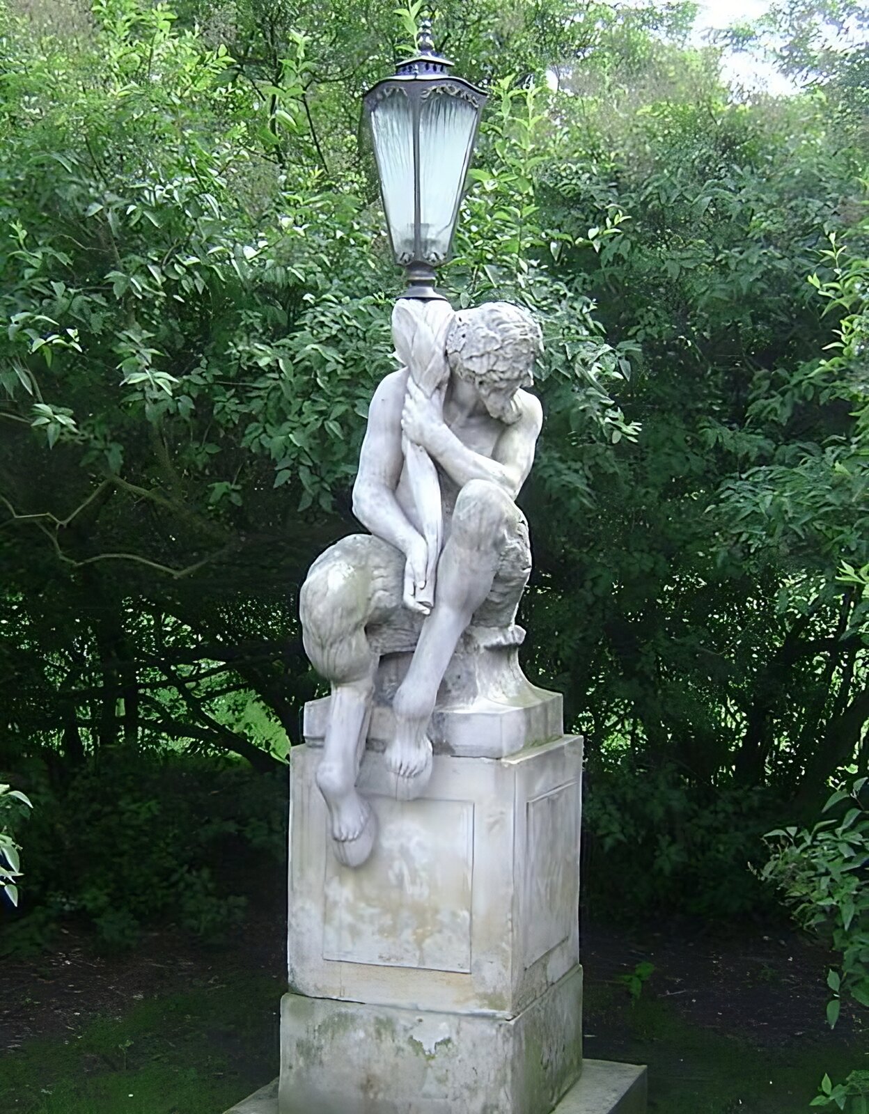 Zdjęcie przedstawia kamienny posąg Satyra sprzed 1774 roku siedzącego na cokole w pozycji melancholijnej i trzymającego latarnię jako symbol oświecenia. Twarz Satyra wyraża rozczarowanie światem rozświetlonym przez światło latarni.