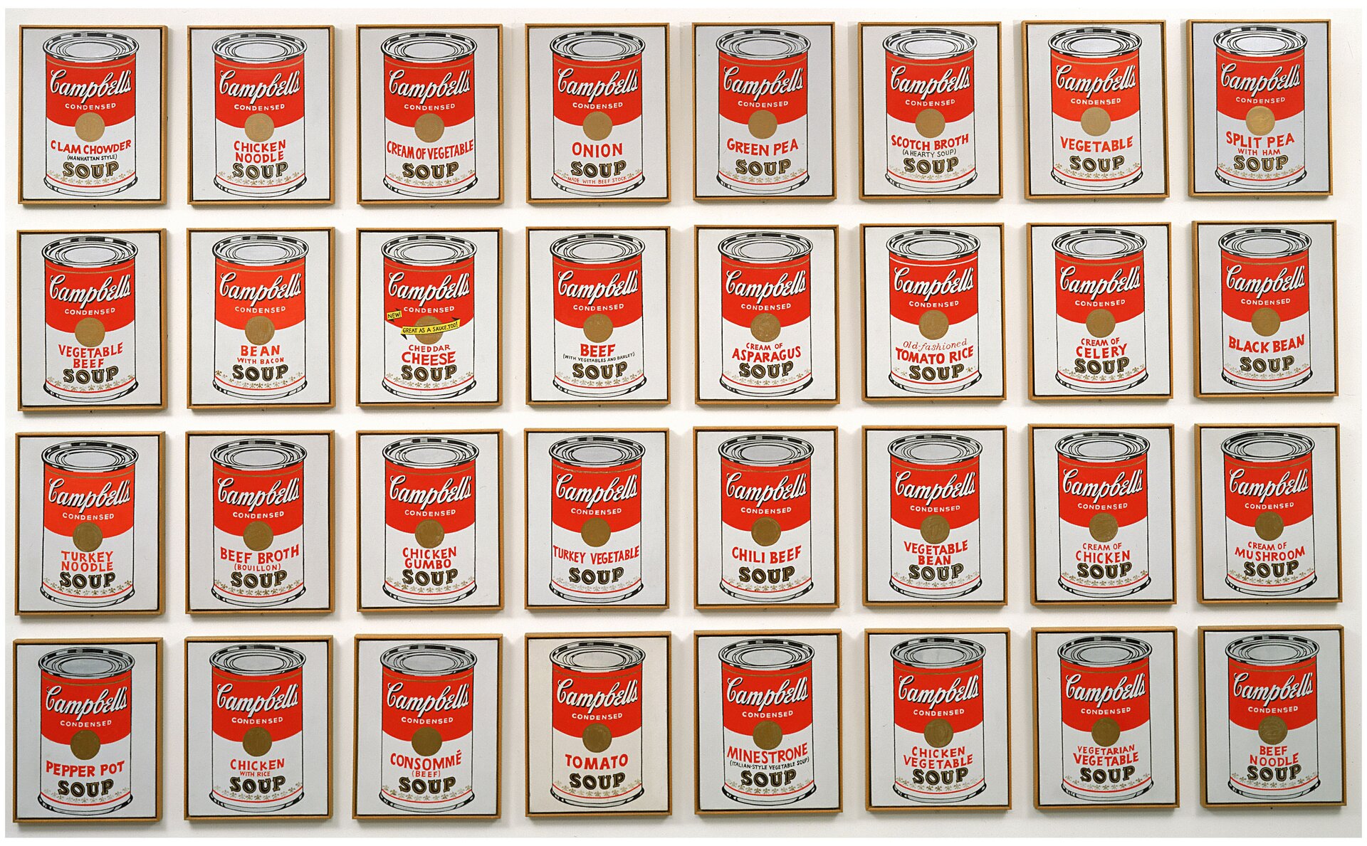 Zdjęcie przedstawia ilustracje puszek zupy, każda znajduje się w osobnej ramce, ułożona w równych rzędach. Każda puszka jest czerwono - biała. Na górze mają nazwę marki - Campbell's, a na dole - nazwę smaku. Puszki nadrukowano na białym tle, w brązowych ramkach i powieszono na białej ścianie.