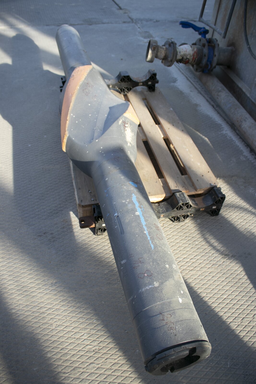 Na zdjęciu widoczny jest stabilizator leżący na drewnianej palecie. Stabilizatory wykorzystywane są w celu zmniejszenia lub zwiększenia kąta skrzywienia otworu.
Stabilizator widoczny na zdjęciu jest położony na drewmianej palecie. Składa się z grubej szarej rury oraz zgrubienia o kształcie świdra które jest widoczne w środkowej jego części. Krawędzie świdra są koloru rdzawego. Przy górnej krawędzi znajduje się walec, który zwęża się ku górze. Na bocznej ścianie walca znajdują się wycięcia do połączenia gwintowego. Stabilizatory są elementami zestawu przewodu wiertniczego przeznaczone do utrzymywania dolnej części przewodu wiertniczego w osi otworu. Dolna część przewodu podlegająca ściskaniu bardzo łatwo ulega wyboczeniu w otworze, a następstwem tego jest skrzywienie osi wierconego otworu. Dlatego też 'podparcie' przewodu o ścianę otworu przy pomocy stabilizatora powoduje utrzymanie obciążników w osi otworu. Średnica zewnętrzna stabilizatora jest bardzo zbliżona do średnicy otworu wiertniczego. 