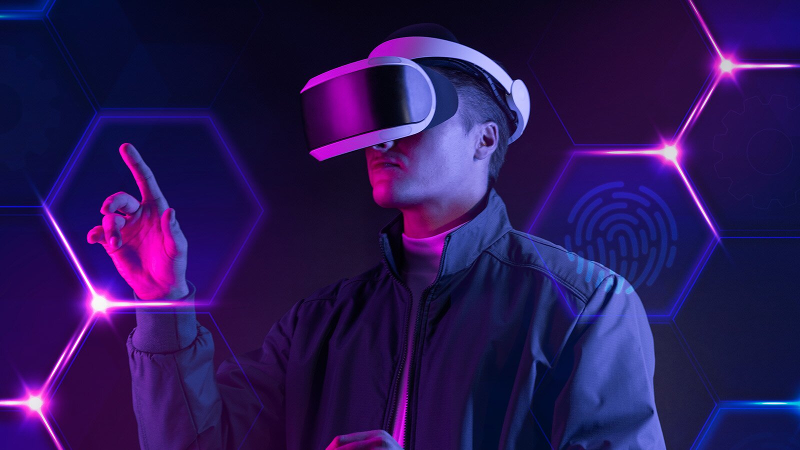 Zdjęcie przedstawia młodego mężczyznę w goglach VR. W przestrzeni wyświetlają się sześciokąty, Jen z nich mężczyzna dotyka palcem wskazującym. 