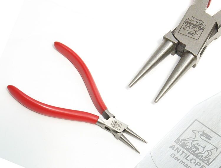 Zdjęcie przedstawia kleszcze okrągłe oraz zbliżenie na ich część z okrągłymi szczękami. Kleszcze składają się z dwóch rękojeści obciągniętych osłoną PCV i szczypców. Szczypce kleszczy są rozwarte i posiadają okrągłe szczęki zakończone spiczasto.