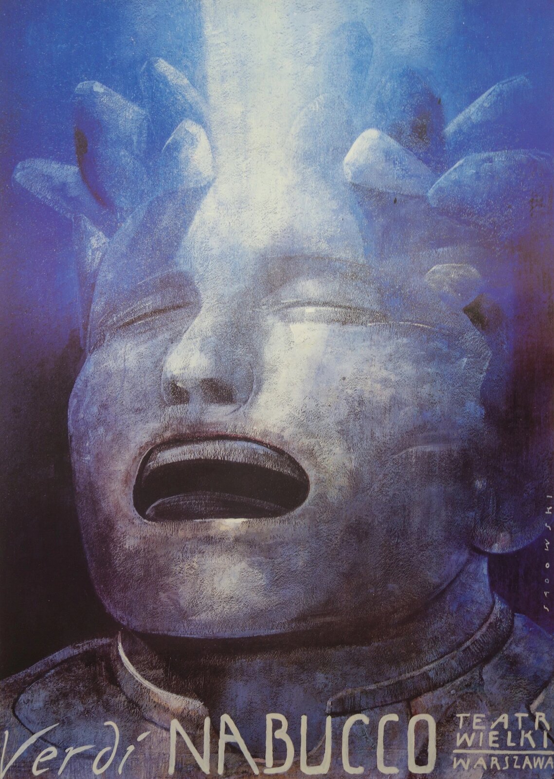 Ilustracja przedstawia plakat promujący operę „Nabucco” Giuseppe Verdiego z 1993r. Ilustracja jest w czarnym, niebieskim, szarym oraz białym kolorze. Postać ma szarą, szerszą twarz, zamknięte oczy oraz szeroko otwarte  usta. Włosy są szpiczaste oraz niebieskie. Od górnej części zdjęcia wpada na twarz promień białego światła. W dolnej części ilustracji został umieszczony jasny napis pt. „Verdi NABUCCO” obok znajduje się mniejszy napis pt. „Teatr Wielki Warszawa”.