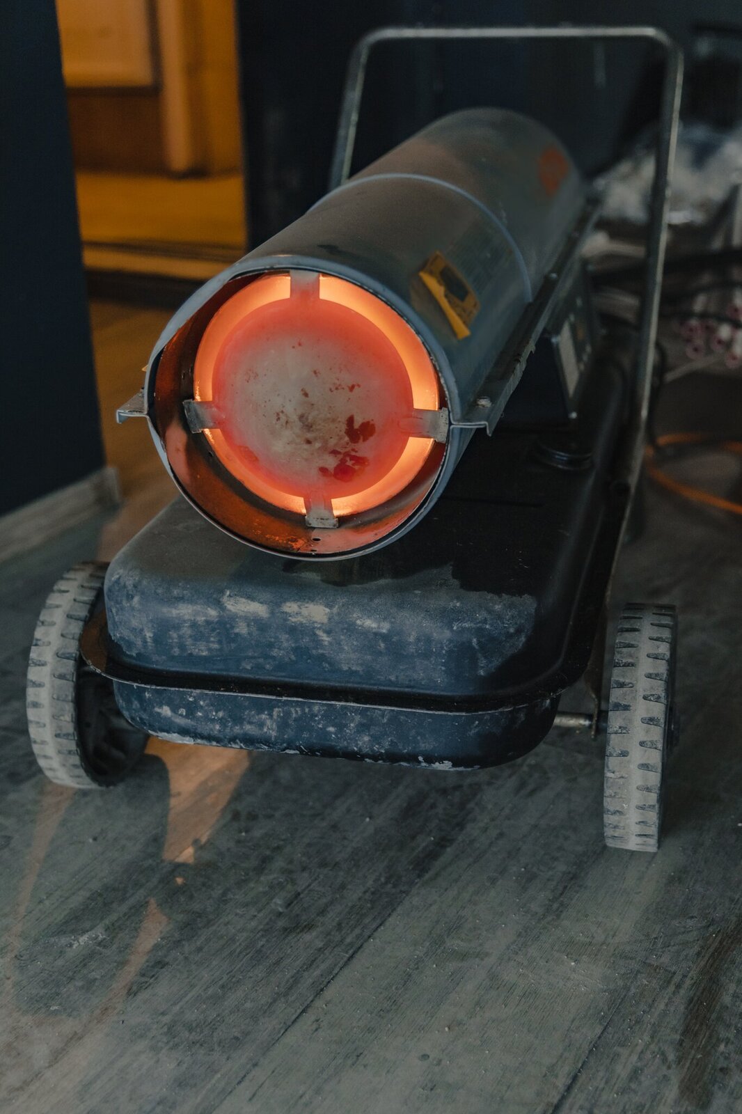 Na zdjęciu przedstawiono nagrzewnicę. Urządzenie znajduje się na platformie wyposażonej w kółka, co umożliwia jego transport. Grzałka znajduje się w podłużnej obudowie w kształcie walca.