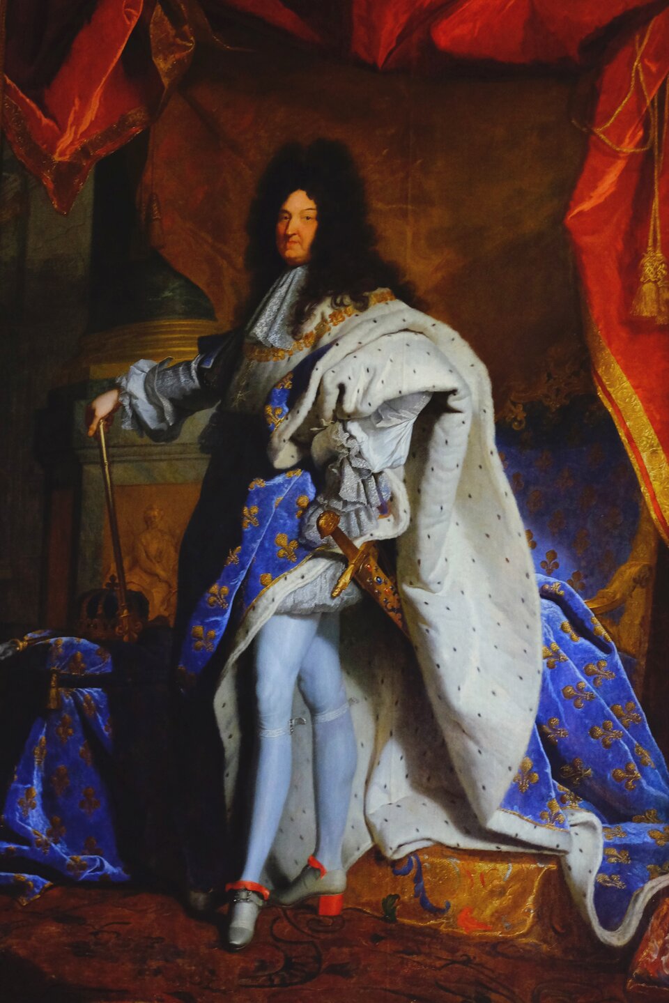 Obraz przedstawia portret króla Ludwika XIV, który stoi w pozie  en trois quarts  [czytaj: trła katr]. Patrzy w stronę widza. Król jest bogato ubrany, na głowie ma czarną perukę z kręconymi włosami sięgającymi do ramion. Na ramionach ma narzucony niebieski płaszcz z naszytymi złotymi liliami, podbity futrem z gronostajów. Jest ubrany w srebrny surdut z koronkowym żabotem, krótkie spodnie, szeroko marszczone, sięgające do połowy ud. Na nogach ma białe pończochy, na stopach srebrne trzewiki z czerwonymi kokardami i obcasami. Przy lewym boku wisi złoty miecz, wysadzany drogimi kamieniami. Lewą rękę wspiera na biodrze. W prawej trzyma berło skierowane w dół, oparte na stołku, na którym leży złota korona.  Jest ona w cieniu, ledwie widoczna. Za jego plecami znajduje się tron, obok stoi kolumna. Nad głową króla wisi czerwona kotara ze złotymi ozdobami.