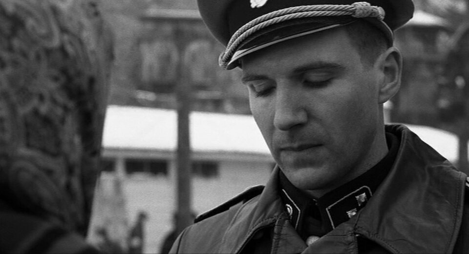 Zdjęcie przedstawia Gӧtha. To młody mężczyzna w niemieckim mundurze i skórzanym płaszczu. Mężczyzna rozmawia z kobietą w chustce na głowie.