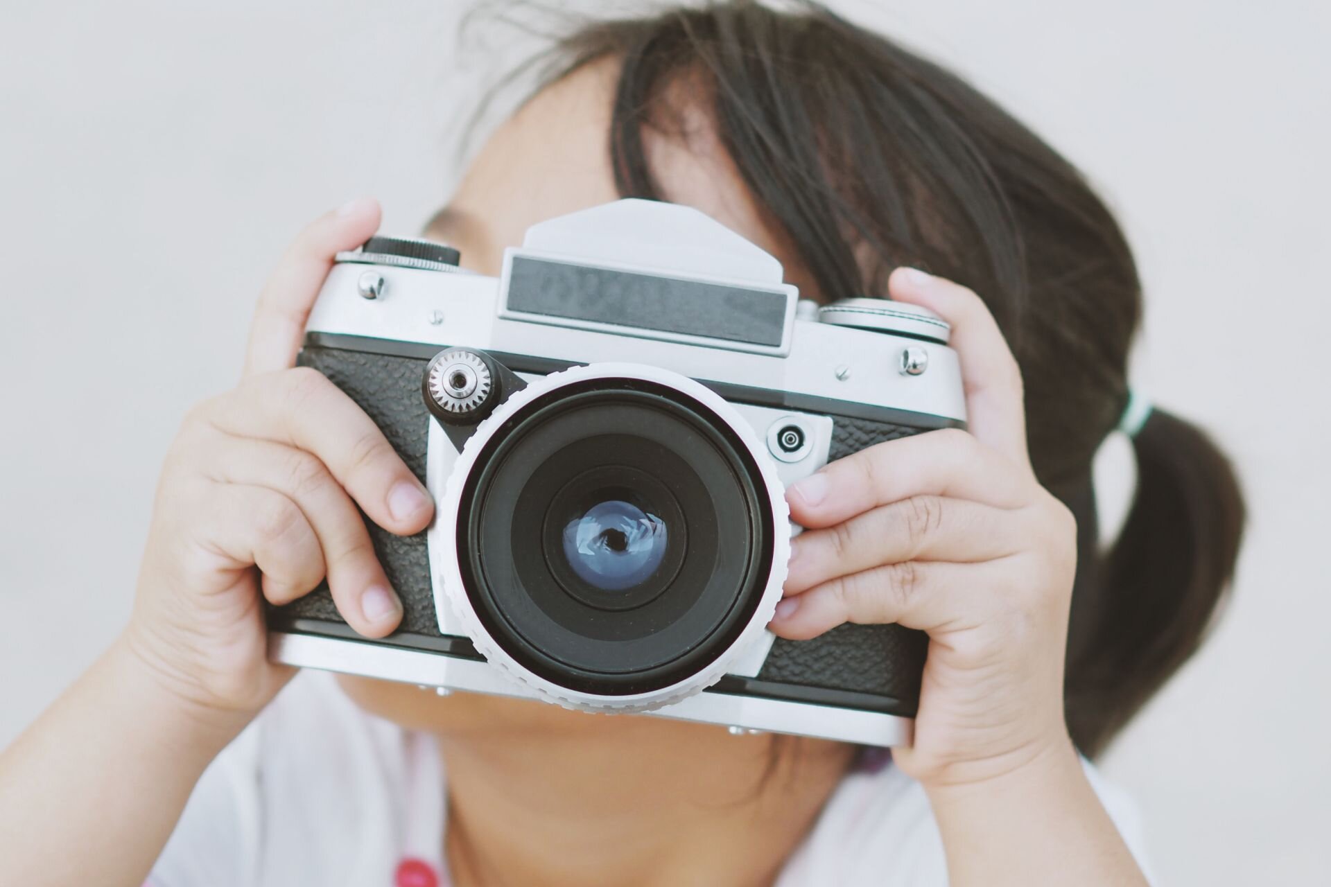 Ilustracja przedstawia dziewczynkę z aparatem fotograficznym.