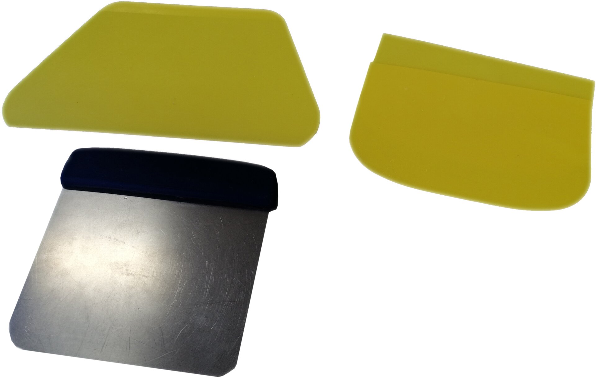 Zdjęcie przedstawia skrobki cukiernicze. Widoczne są trzy skrobki, na dole po lewej skrobka metalowa – kwadratowa część pracująca, z zaokrąglonymi narożnikami, z czarnym taśmowatym elementem u góry symbolizującym część służącą do trzymania. U góry widoczne są dwie skrobki wykonane z tworzywa w kolorze: po lewej kwadratowa z zaokrąglonymi narożnikami, po prawej kwadratowa z półkoliście zakończoną dolną częścią pracującą.