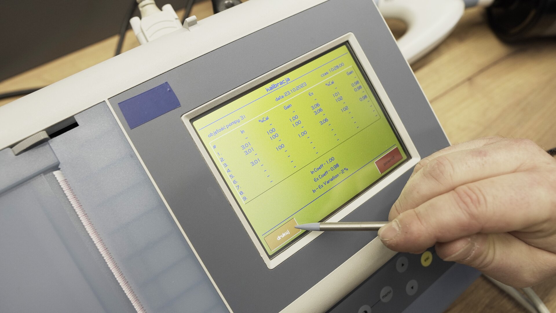 Na zdjęciu pokazano przybliżenie ekranu spirometru. Technik wybiera na klawiaturze ekranowej przycisk drukuj.
