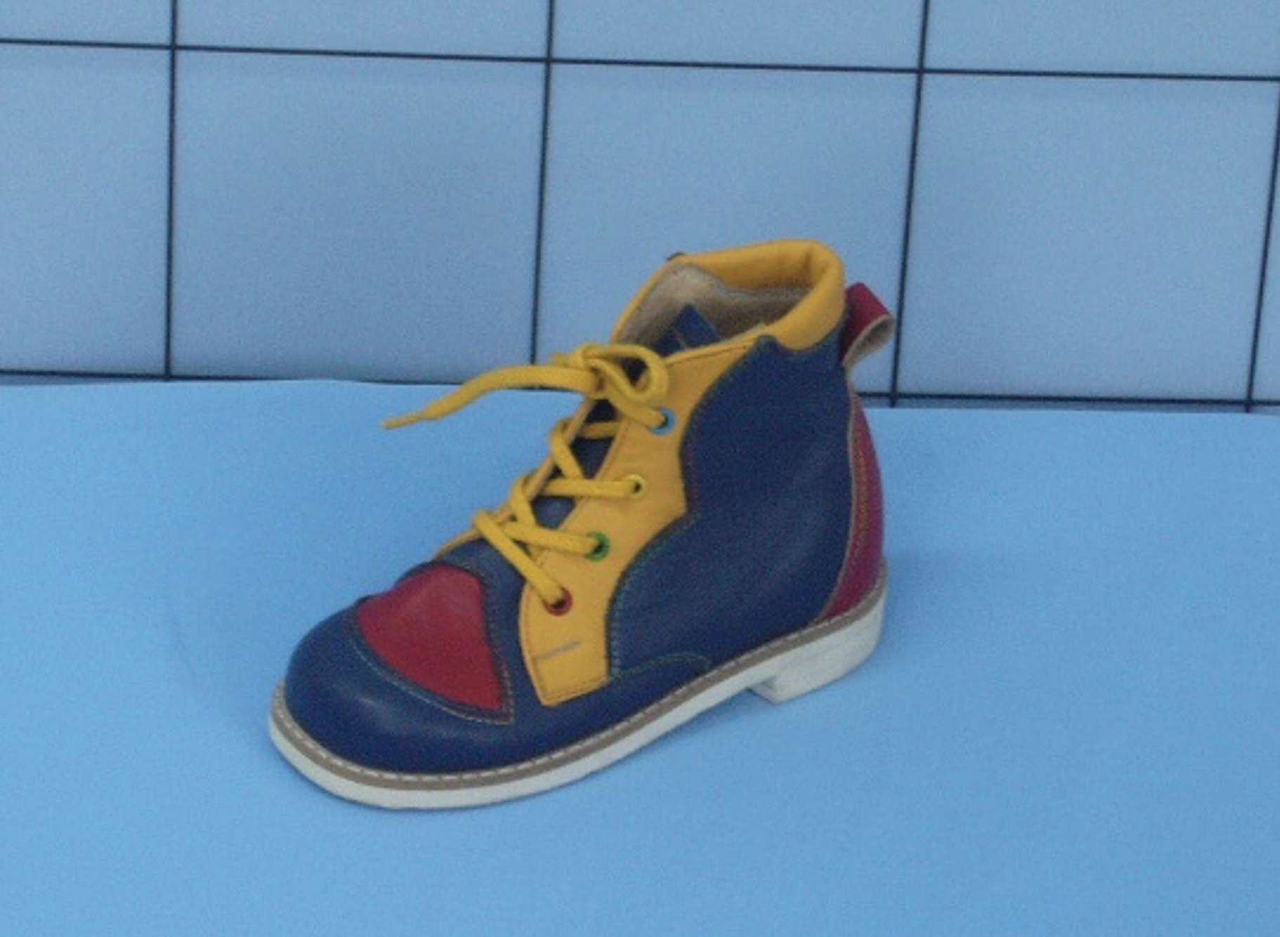 Zdjęcie przedstawia kolorowy but dziecięcy ze sznurowaniem.