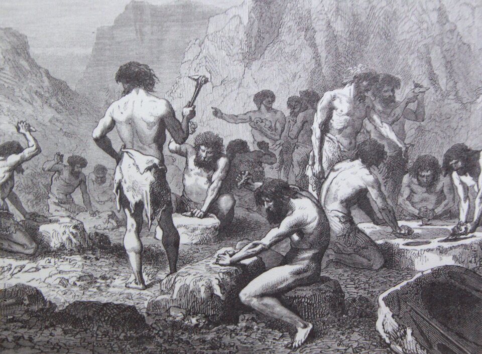 Ilustracja ukazuje rycinę Louisa Figuiera "Człowiek pierwotny - warsztat narzędziowy". Przedstawia scenę z życia ludzi prehistorycznych.Na ilustracji widoczna jest grupa osób zaangażowanych w obróbkę kamienia. Centralną postacią jest mężczyzna, który stoi i pracuje na dużym blokiem kamienia, prawdopodobnie tworząc narzędzie lub broń. Wokół niego znajdują się inni członkowie grupy, obserwujący jego działania lub zajmujący się własnymi zadaniami związanymi z obróbką kamienia. 