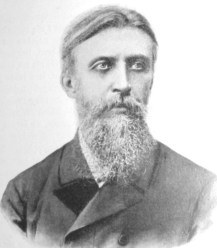 Ilustracja przedstawia mężczyznę w średnim wieku. Jest to osoba z gładko zaczesanymi włosami, długą brodą oraz wąsami. Ubrana w elegancki garnitur.