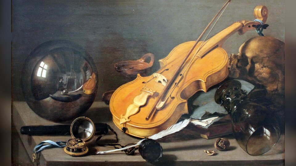 Obraz przedstawia martwą naturę. Na stole znajdują się porozrzucane przedmioty: przewrócony, szklany kielich, czaszka ludzka, książka, skrzypce, zegarek, kałamarz i pióro gęsie, szklana kula. 