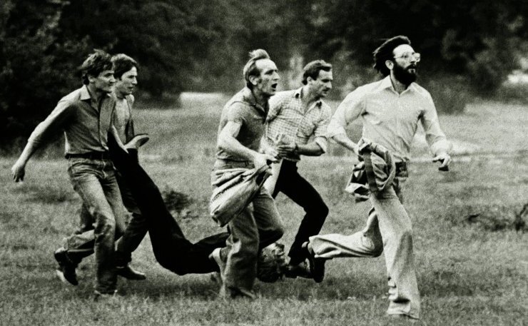 Zdjecie przedstawia jedno z najsłynniejszych zdjęć okresu stanu wojennego, na zdjeciu czterech mężczyzn, biegnąc niesie rannego człowieka.