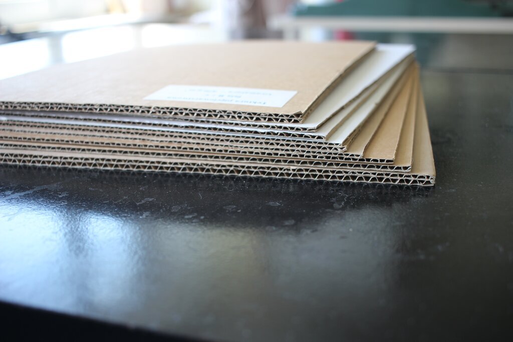 Zdjęcie przedstawia kilka arkuszy pięciowarstwowej tektury falistej. Składa się ona z dwóch zewnętrznych warstw płaskich, dwóch warstw pofalowanych oraz wewnętrznej warstwy płaskiej pomiędzy nimi.