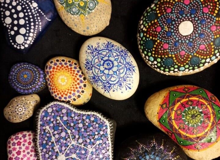 Zdjęcie przedstawia polne kamyki ozdobione kropkowanym ornamentem, niekiedy symetrycznym, w którym powtarzają się różnej wielkości kropki i kreski.   