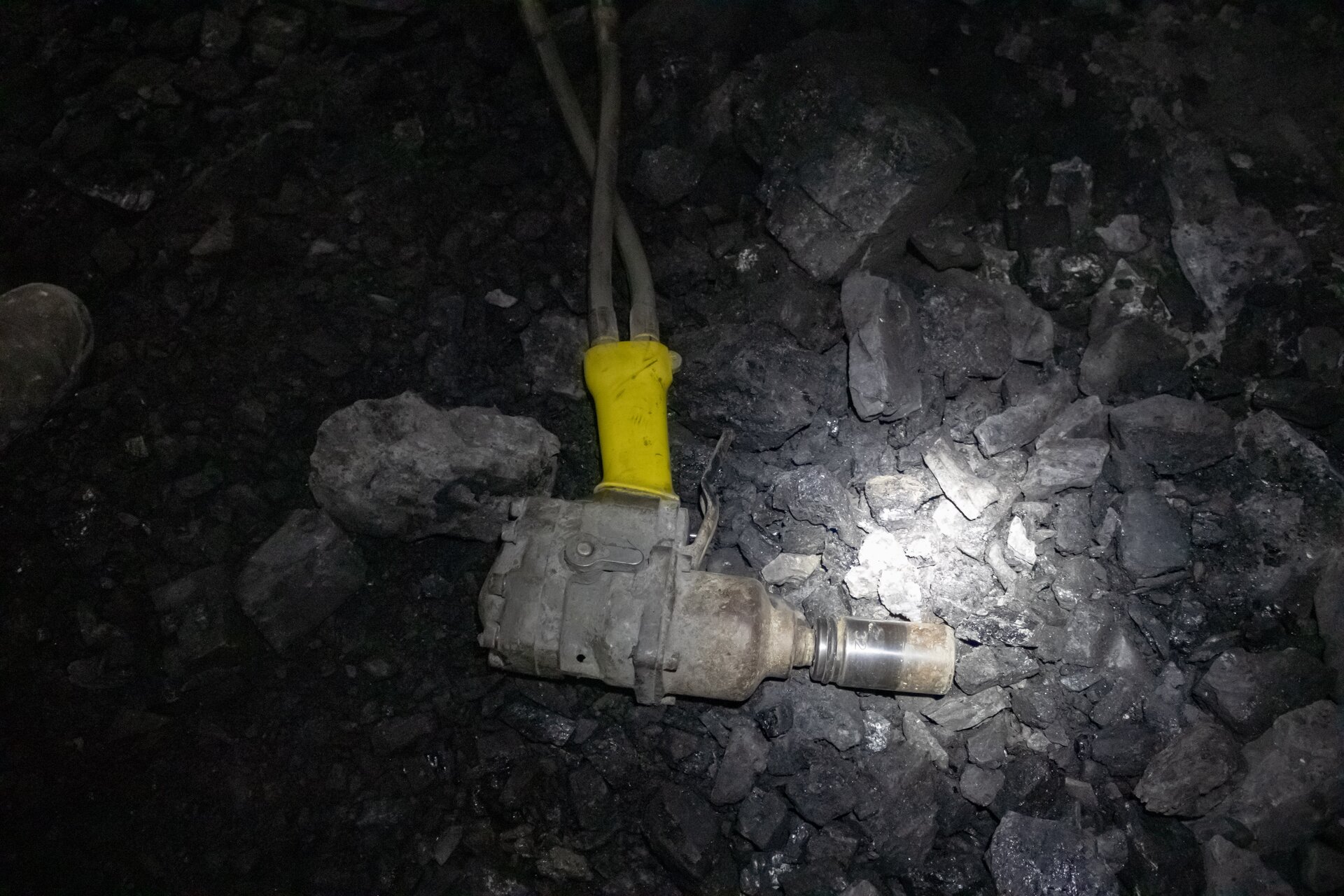 Na zdjęciu widoczny jest klucz hydrauliczny. Klucz przypomina kształtem pistolet. Różnicę z pistoletem stanowi organ roboczy. Lufa klucza jest o kształcie cylindra na który założony jest klucz nasadowy. Klucz nasadowy jest o kształcie cylindra. Do podstawy klucza dochodzą dwa kable. Widoczny na zdjęciu klucz leży na spągu wyrobiska. 