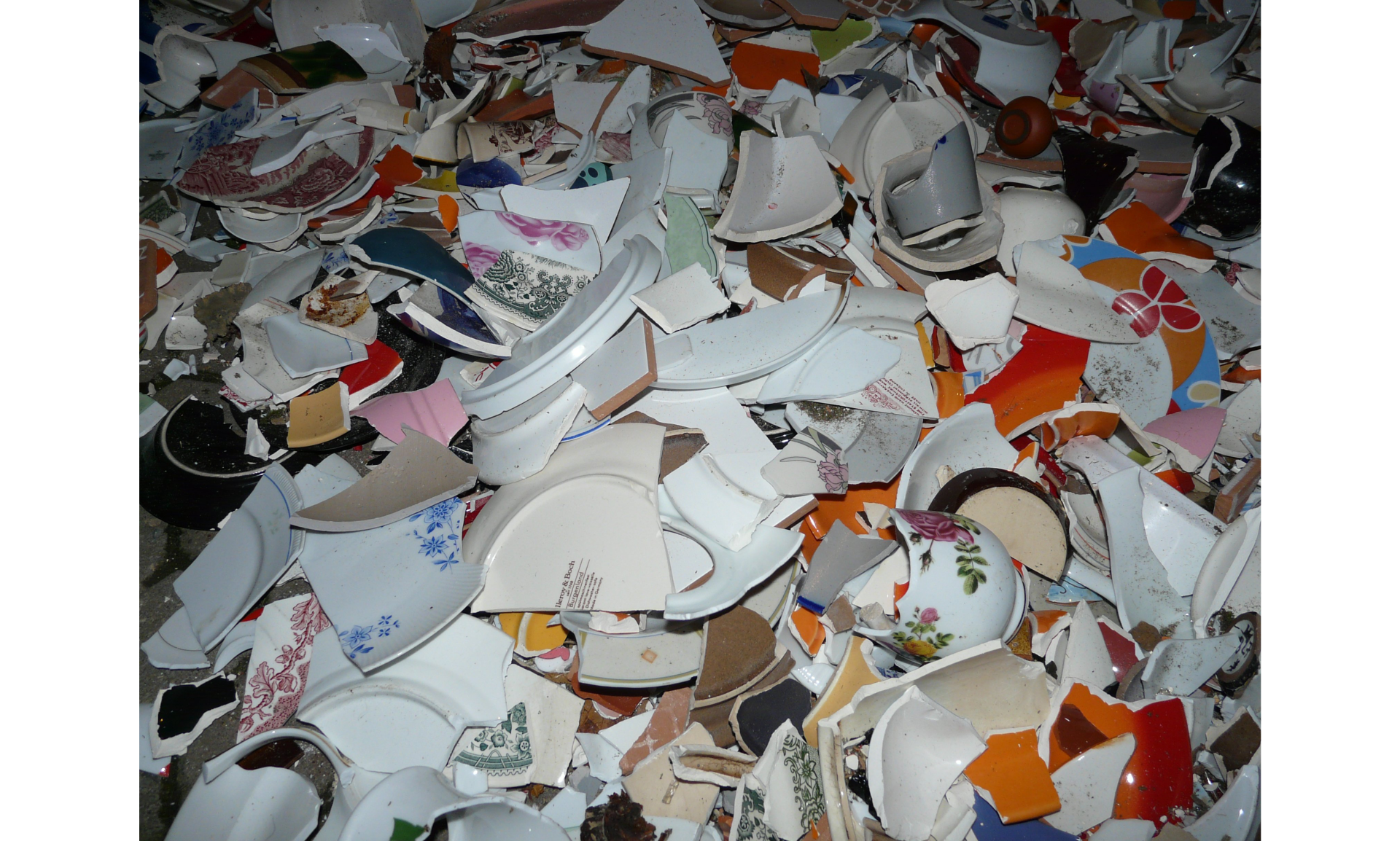 Zdjęcie przedstawia stłuczone przedmiotów z porcelany, widoczne liczne fragmenty różnych naczyń.