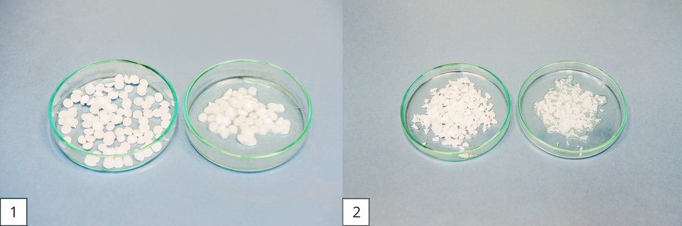 Ilustracja przedstawia higroskopijność wodorotlenków sodu i potasu. Składa się z dwóch zdjęć. Na fotografii po lewej stronie, oznaczonej numerem jeden, znajdują się dwie stojące obok siebie na tle szarego blatu szalki Petriego. Szalkę po lewej stronie wypełniono świeżymi, białymi granulkami wodorotlenku sodu. W szalce po prawej znajduje się nieco mniejsza ilość tej samej substancji, umieszczonej znacznie wcześniej. Granulki są ciemniejsze i mocno wilgotne, a nawet częściowo rozpuszczone na skutek wchłonięcia wody z powietrza. Na zdjęciu po prawej stronie takie samo zestawienie dla kawałków wodorotlenku potasu. Skrawki w mniejszym stopniu przypominają granulki, a bardziej wióry. Porcja w szalce z prawej strony zebrała już na tyle wody, że ułożyła się ona na powierzchni szkła w małą kałużę.