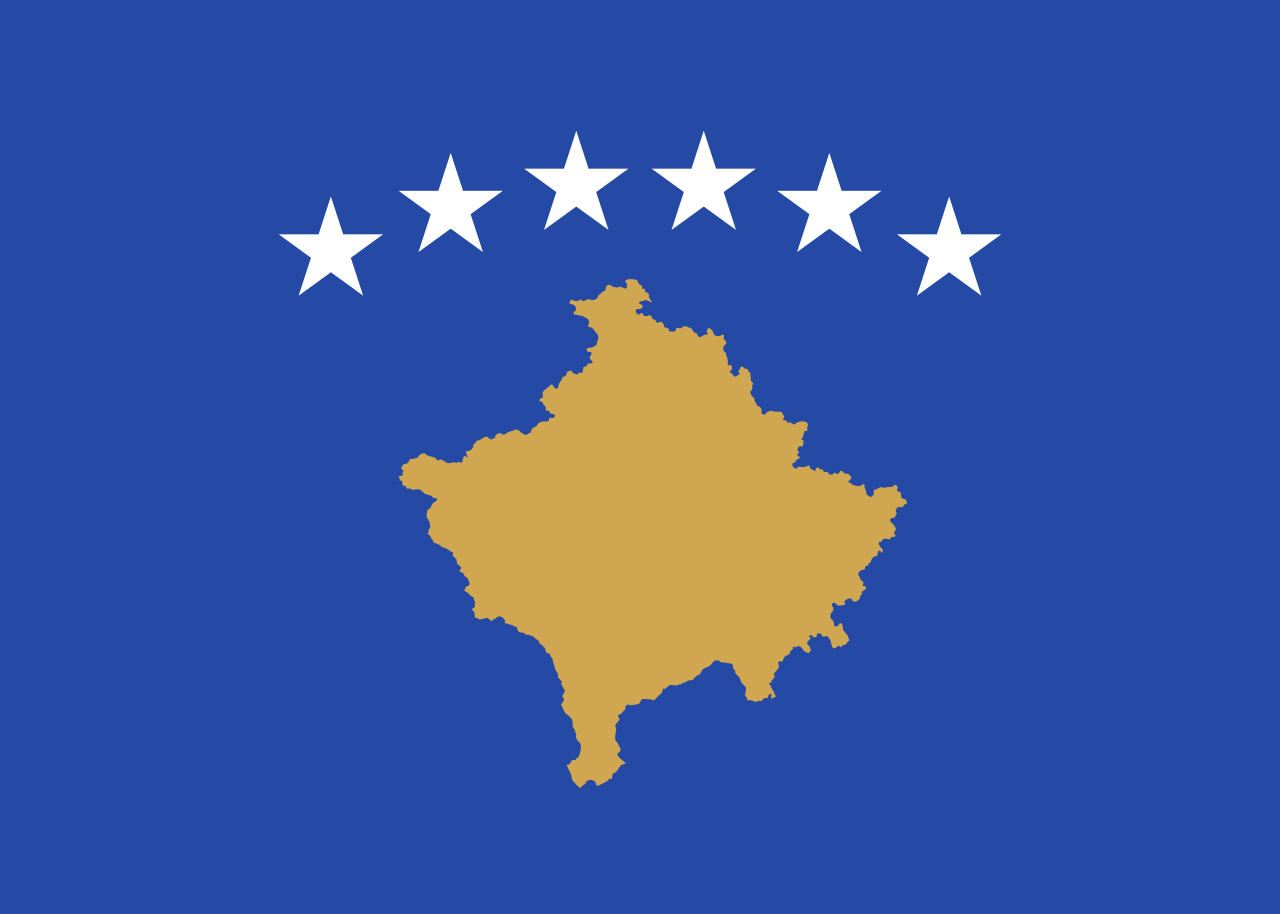 Gragika przedstawia flagę Ksowa. Na niebieskim tle, w centralnej części, umieszczony jest obrys Kosowa w kolorze złotym. Nad nim znajduje się sześć białych gwiazd/