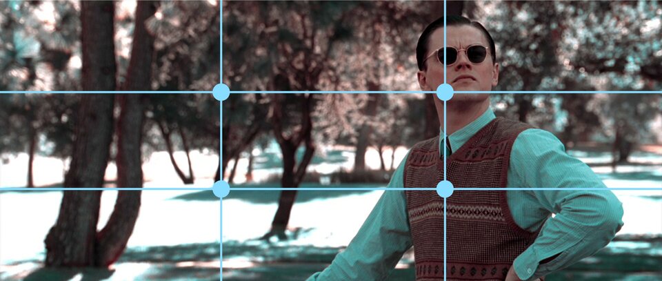 Ilustracja przedstawia Leonardo di Caprio w kadrze z filmu „Aviator”. Na ilustracji znajduje się mężczyzna ubrany w niebieską koszulę oraz wełnianą kamizelkę. W tle ilustracji znajdują się drzewa. Na ilustracji znajdują się dwie poziome oraz dwie pionowe kreski, które tworzą linie podziału kadru. Dzielą ilustrację na dziewięć równych części. Na rogach środkowego prostokąta znajdują się kropki, które wyznaczają mocne punkty kadru. W prawym górnym mocnym punkcie znajduje się twarz mężczyzny, a w dolnym środek klatki piersiowej. W lewym górnym mocnym punkcie znajdują się liście drzew, a w dolnym pień.