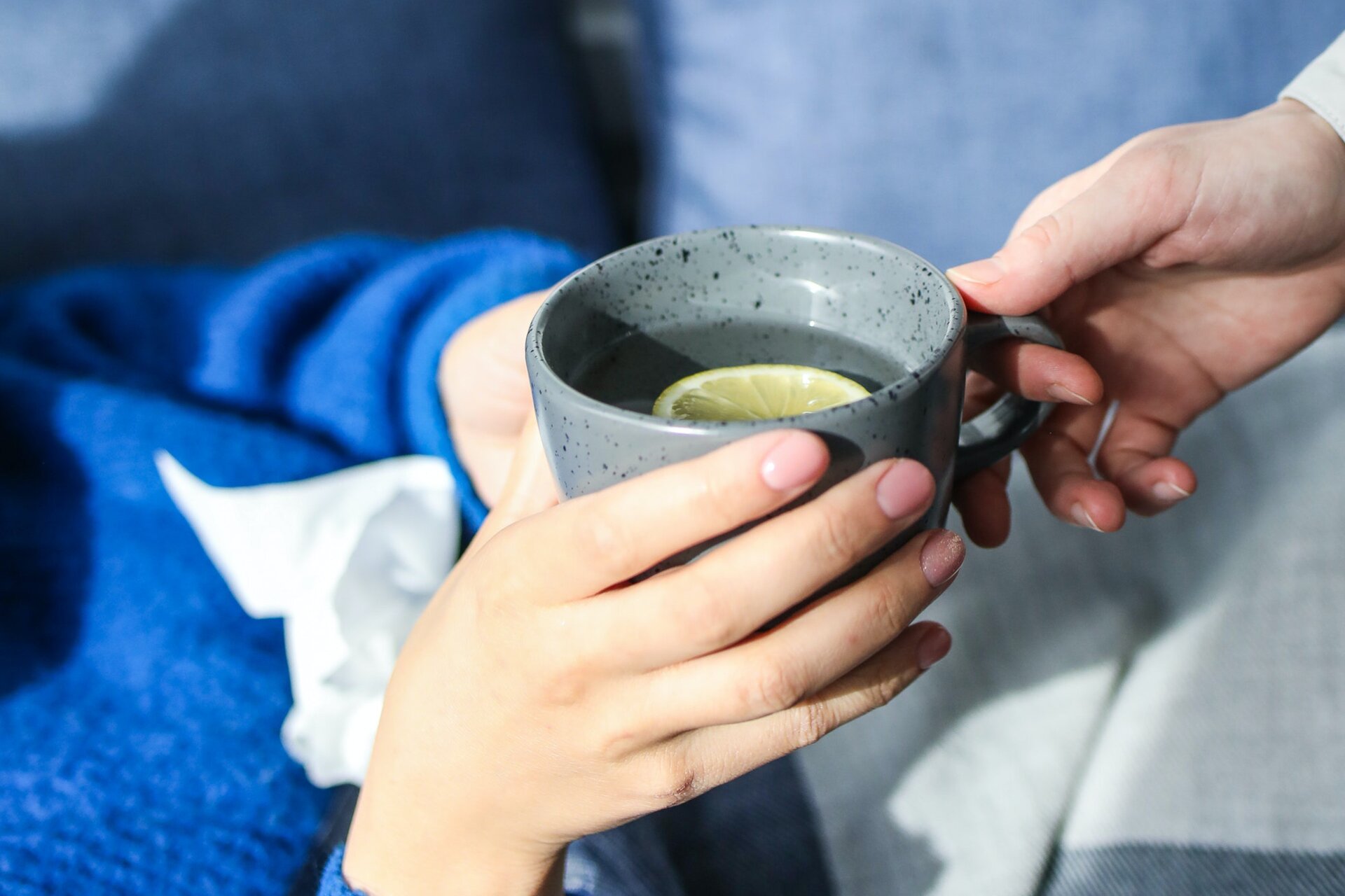 Na ilustracji widoczna jest osoba, która podaje filiżankę herbaty drugiej osobie leżącej w łóżku.