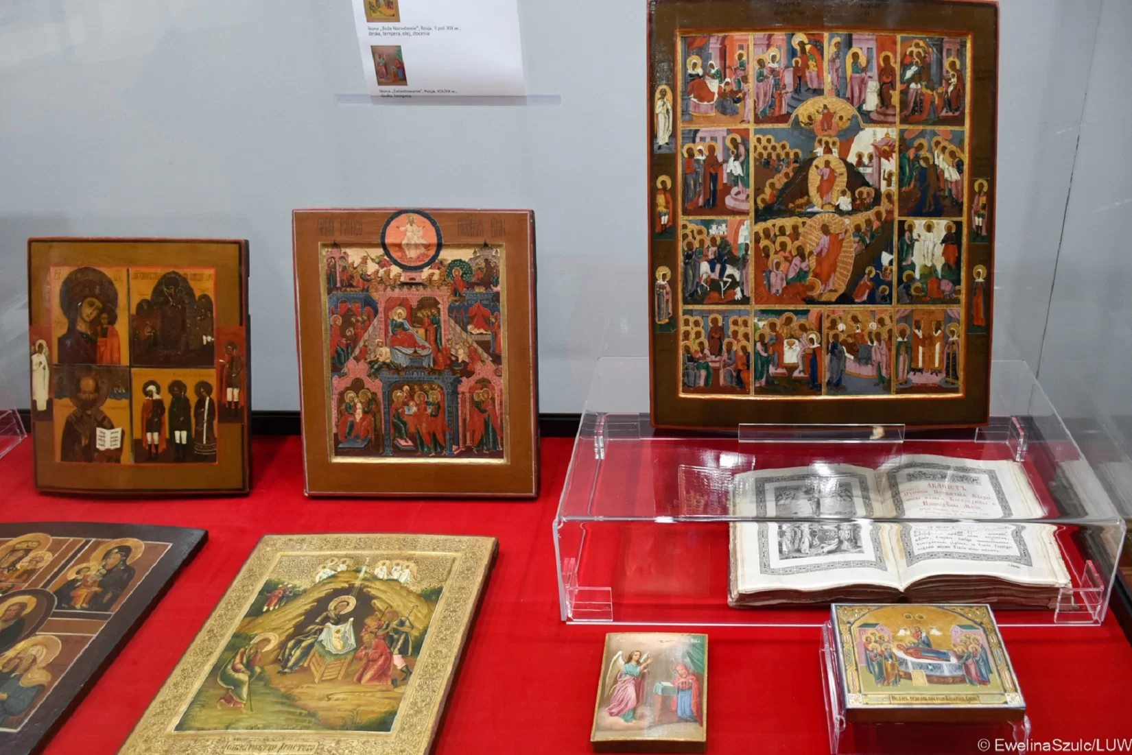 Zdjęcie przedstawia fragment wystawy ikon. Wszystkie osiem ikon umieszczono w szklanej gablocie. Trzy ikony stoją oparte o szybę, a pięć przechowywanych jest w pozycji leżącej – jedna z nich umieszczona została w dodatkowej szklanej gablocie. Każda z ikon przedstawia osobę świętą (przeważnie Maryję z dzieciątkiem) lub opisuje historię Jezusa.  