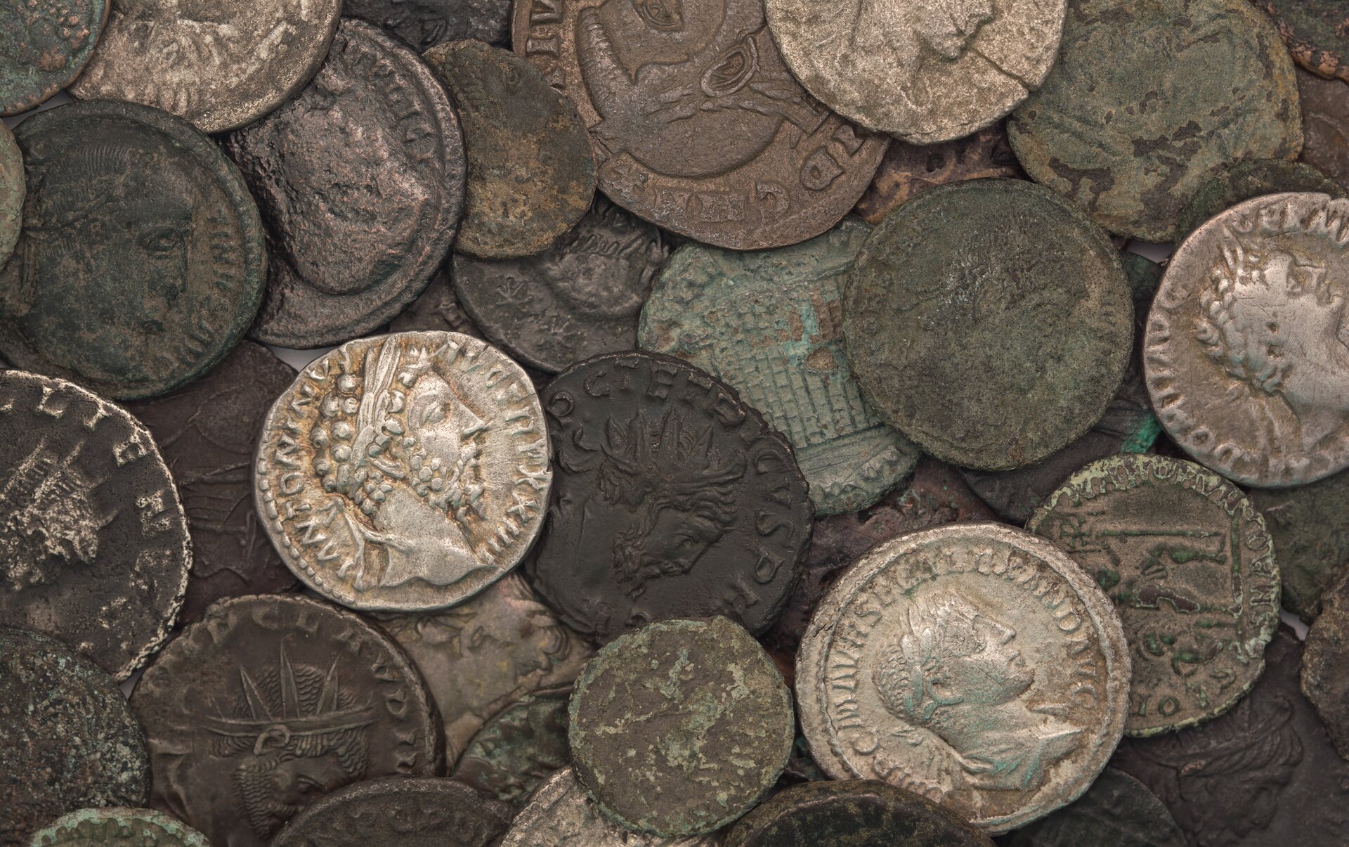Ilustracja przedstawia stare monety Imperium Rzymskiego. Monety ozdobione są popiersiami antycznych postaci.