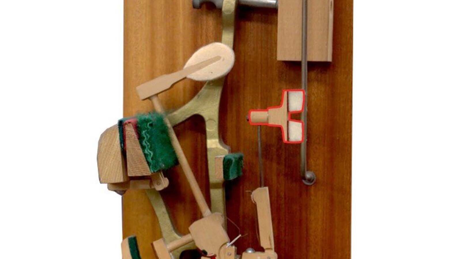 Zdjęcie przedstawia podzespół mechanizmu pianinowego lub fortepianowego jakim jest tłumik. Element został zaznaczony czerwoną obwódką.