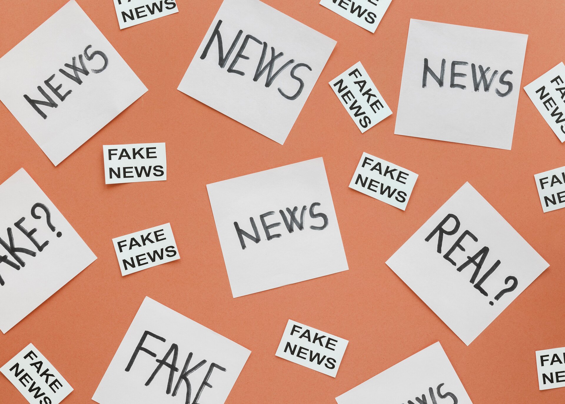 Zdjęcie przedstawia karteczki przyklejone na ścianie, na których widoczne są słowa w języku angielskim: NEWS, FAKE NEWS, REAL, FAKE.