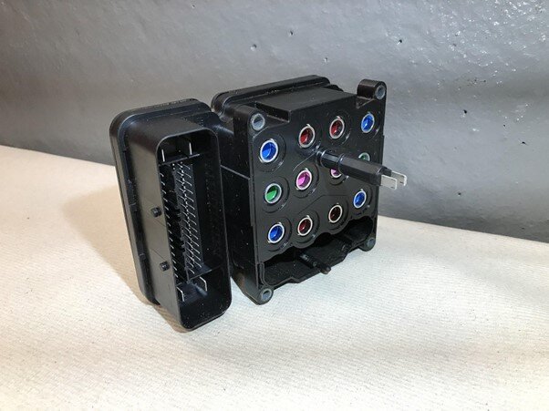 Grafika przedstawia sterownik ABS. Jest to mała skrzynka z gniazdami i wejściami na różne kable i wtyczki.