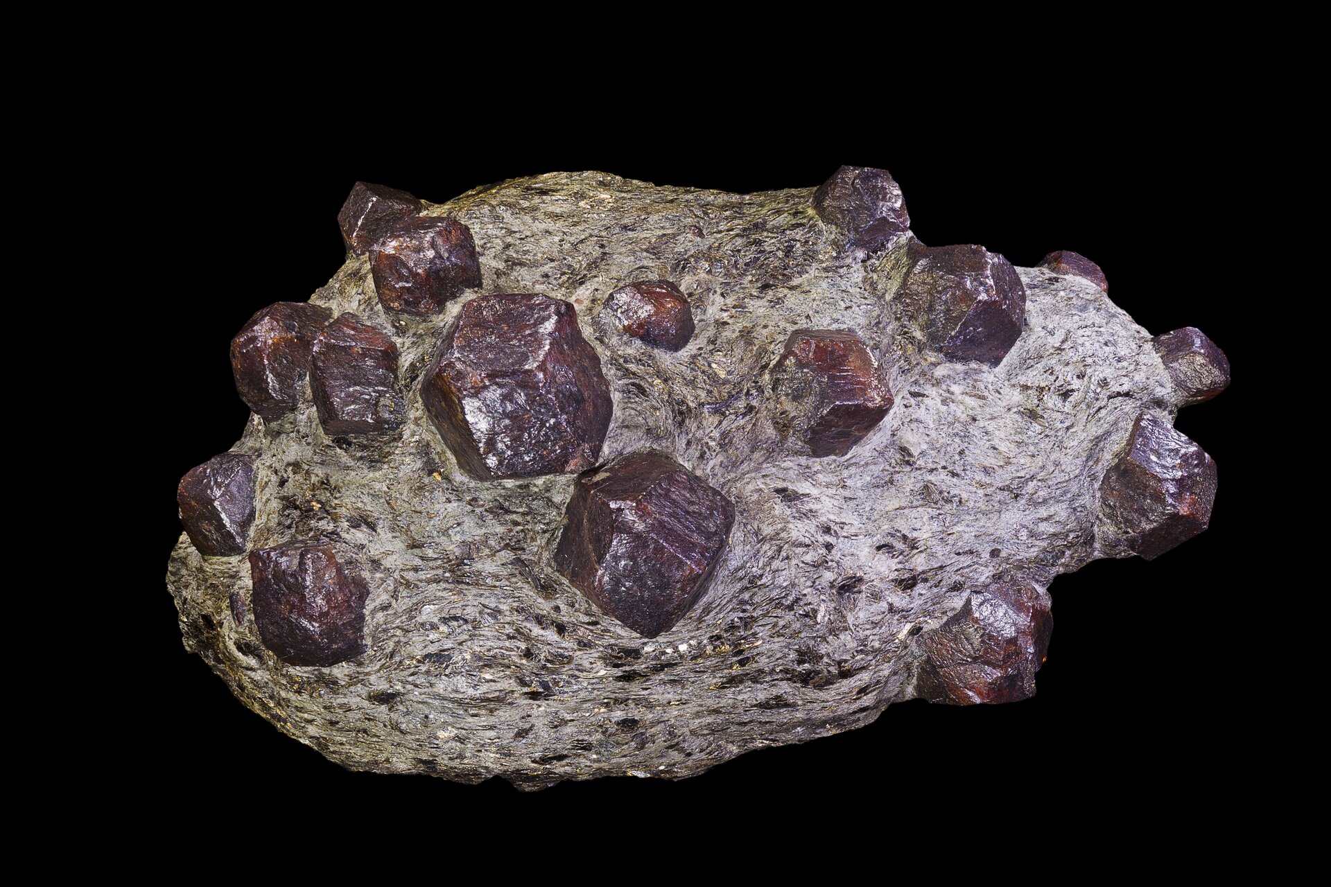 Zdjęcie ukazuje kamień, w którym znajdują się fioletowe niewielkie wielościany o fioletowej barwie.  