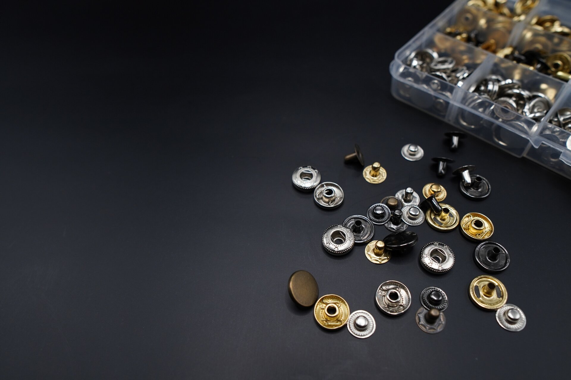 Na zdjęciu widoczne są różnokolorowe, metalowe, okrągłe elementy przypominające guziki. 