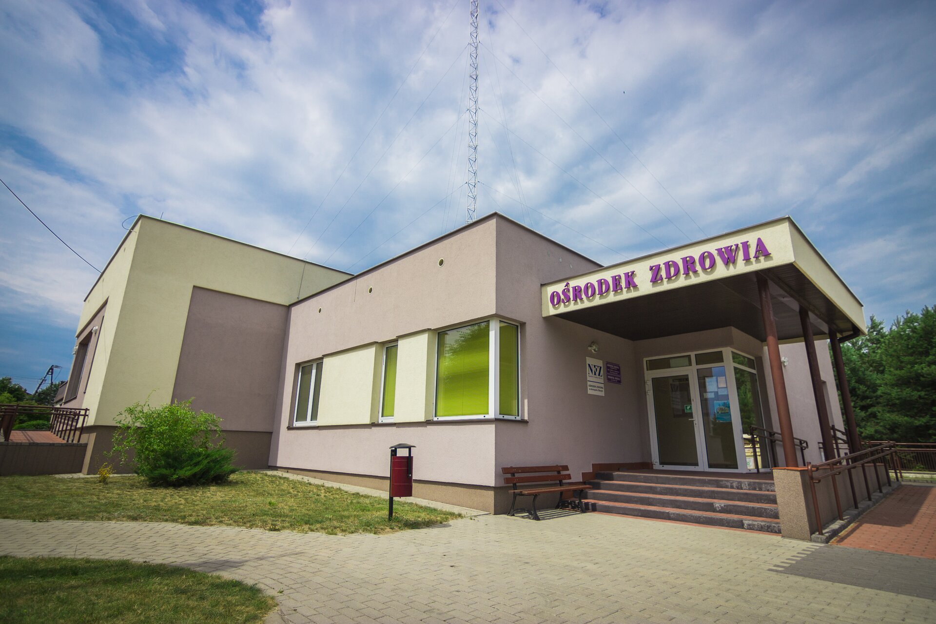 Zdjęcie przedstawiające niski budynek. Nad drzwiami znajduje się napis "ośrodek zdrowia". Do budynku prowadzi kilka schodków.