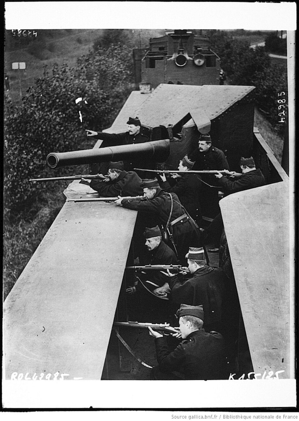 W otwartym wagonie znajdują się żołnierze. Opierają broń na ścianie wagonu i celują przed siebie. Na końcu znajduje się pancerne działo. Żołnierze ustawieni są w szeregu, broń mają skierowaną w lewą stronę.