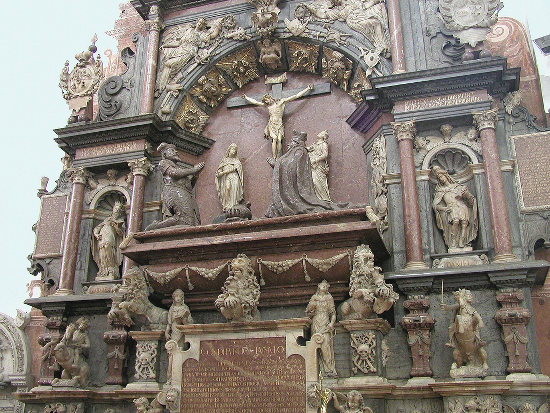 Ilustracja o kształcie poziomego prostokąta przedstawia przyścienny nagrobek Zuzanny i Janusza Ostrogskich. Architektoniczne tło wykonane jest z czerwonego marmuru. Centralne pole zajmuje wsparty na lwach sarkofag, na którym klęczą postacie fundatora księcia Janusza wraz z żoną Zuzanną, umieszczone na tle płaskorzeźby ze sceną Ukrzyżowania. Niżej, po obu stronach tablicy inskrypcyjnej umieszczono personifikacje cnót: Wiarę i Nadzieję. W zwieńczeniu, w prostokątnym polu, znajduje się płaskorzeźbiona scena zmartwychwstania Chrystusa. Scenę centralną otaczają figury umieszczone w niszach lub wolnostojące, wśród nich zbrojni rycerze na koniach w galopie, chorągwie, bębny, działa. Dekoracje stanowią liczne napisy, tarcze herbowe. Nagrobek znajduje się na tle białej ściany.