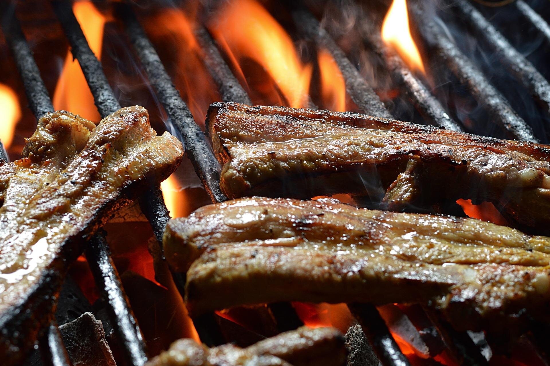 Zdjęcie przedstawia mięso pieczone nad ogniem. Podpis: Zurück zu den Wurzeln: Das Grillen über offenem Feuer erlebt derzeit eine Renaissance.