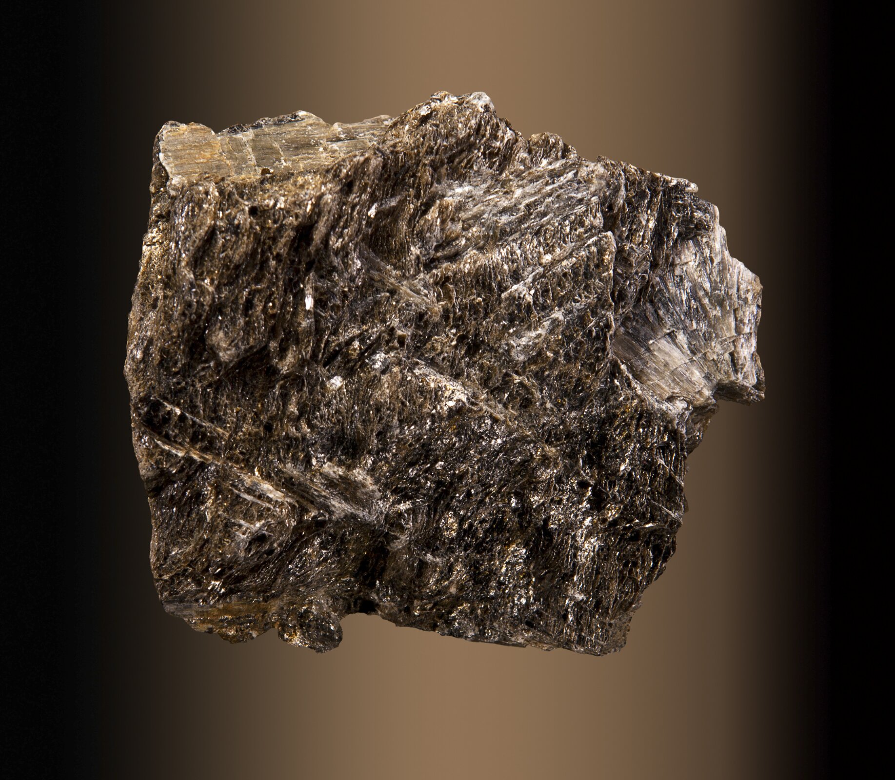 Zdjęcie przedstawia brązowy minerał o włóknistej budowie. Sprawia wrażenie kruchego.    