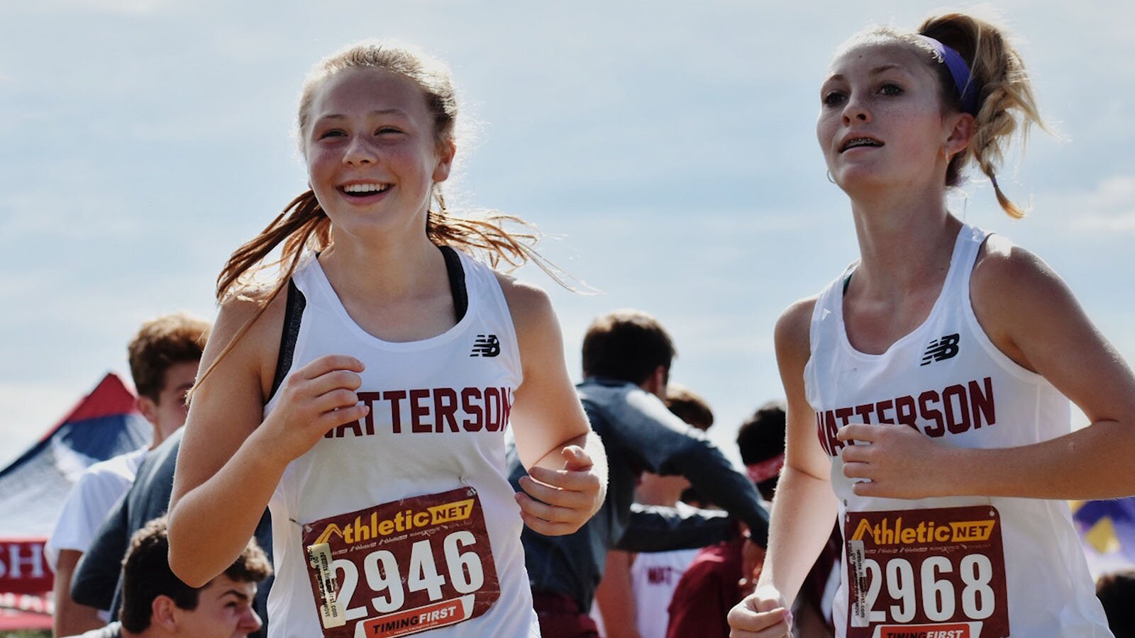 Zdjęcie przedstawia dwie uśmiechnięte kobiety, od pasa w górę. Kobiety mają na sobie stroje do biegania. Obie mają koszulki na ramiączka na których jest napis "HATTERSON", pod którym mają naklejone kartki z numerami. 