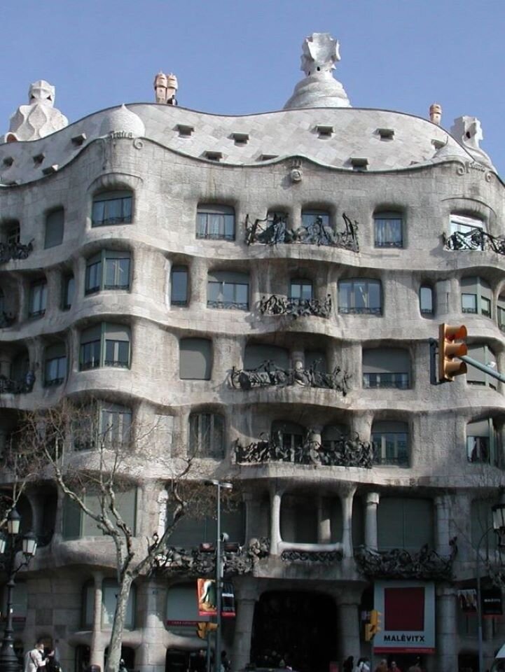 Ilustracja interaktywna przedstawia fasadę budynku Casa Milà w Barcelonie zaprojektowany przez Antonia Gaudiego. Budynek jest wielokondygnacyjny i ma falisty kształt. Balkony zdobią kute z żelaza balustrady, przybierające kształt wodorostów. Ozdobą fasady są również ptaki, które sprawiają wrażenie szykujących się do odlotu. Dach przypomina skorupę żółwia. 