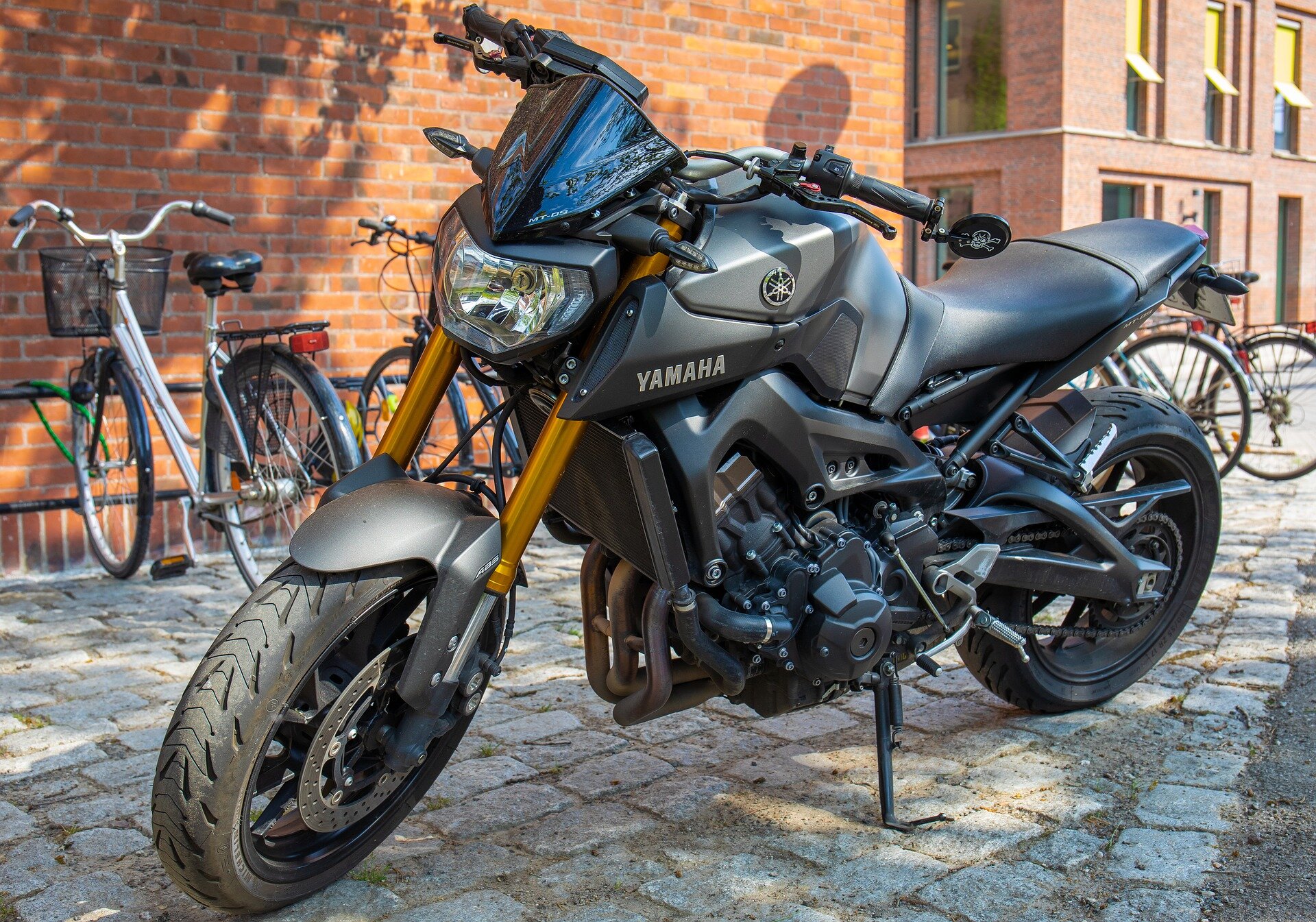 Zdjęcie przedstawia czarny motocykl. Jest zaparkowany na chodniku. 