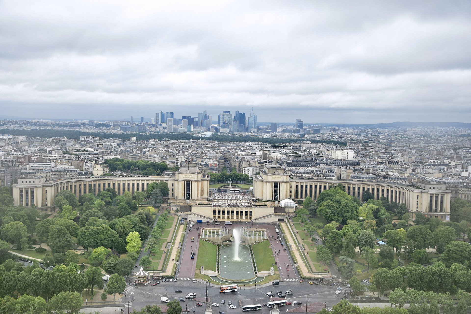 Zdjęcie panoramy miasta, na pierwszym planie rozległe aleje, monumentalna zabudowa, plac z fontanną. Dalej gęsta miejska zabudowa, a w tle szklane wieżowce.