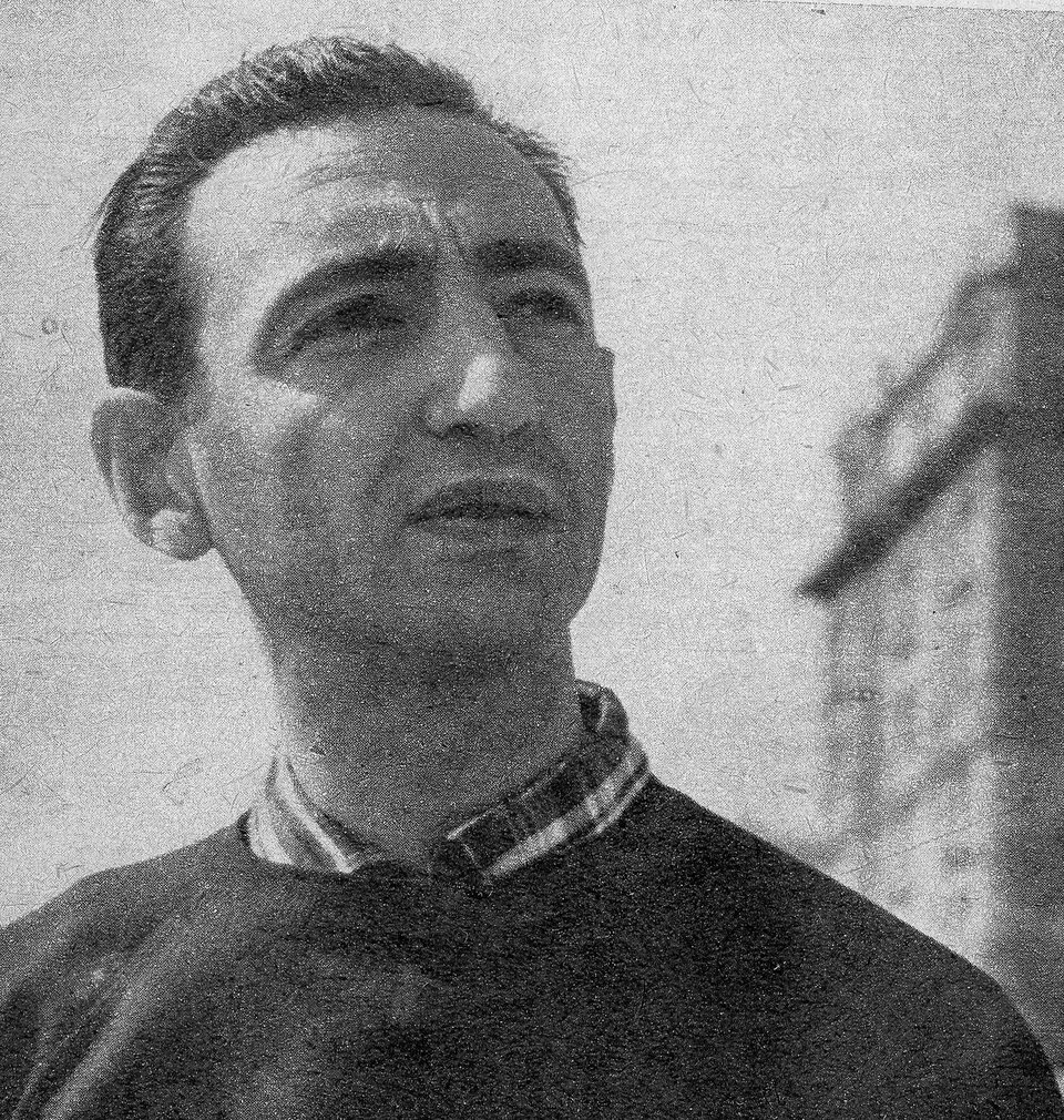 Zdjęcie przedstawia dojrzałego, ciemnowłosego mężczyznę. Jego twarz jest owalna, nos szeroki, wydatny. Oprawa oczu ciemna, wyrazista, usta pełne. Włosy krótkie, zaczesane ku górze, proste. Mężczyzna ubrany jest w koszulę i sweter.